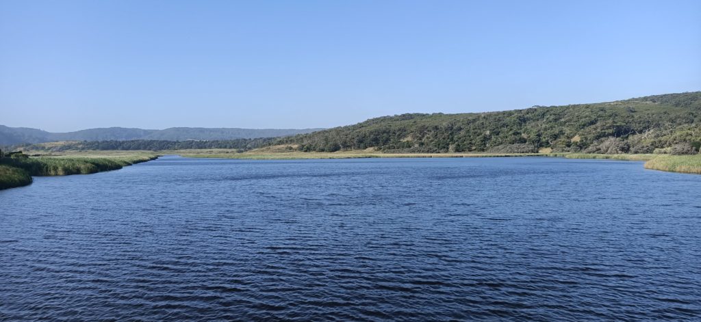 A picture of Aire River at its widest section, there are green hills in the background and a clear blue sky.