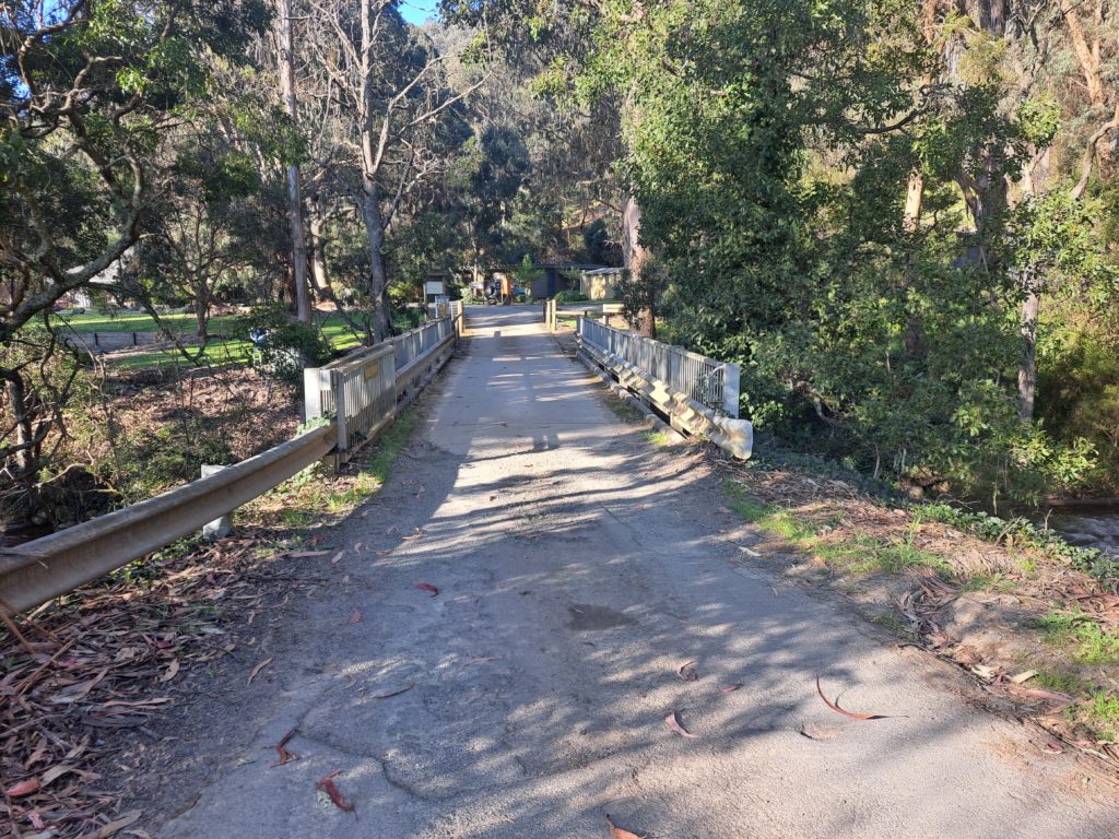 View of a road bridge which is over a river. There are trees lining both sides.